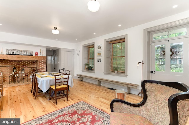 dining area with light wood-type flooring, brick wall, and recessed lighting