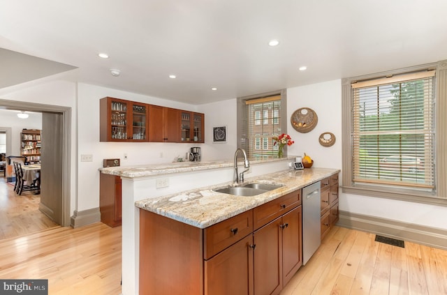 kitchen featuring a sink, dishwasher, baseboards, light wood-style floors, and recessed lighting