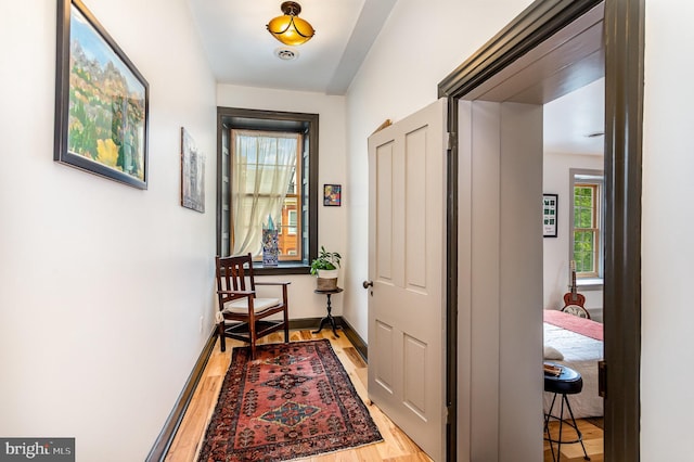 hall with light wood-style floors and baseboards