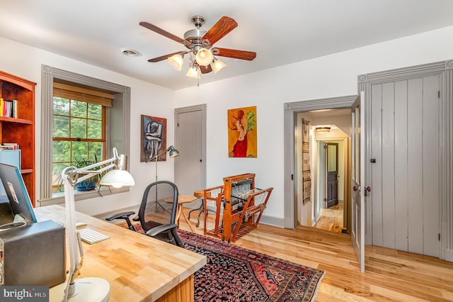 office space with a ceiling fan, light wood finished floors, and baseboards