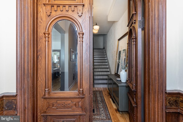 hall featuring stairs, wood finished floors, and arched walkways