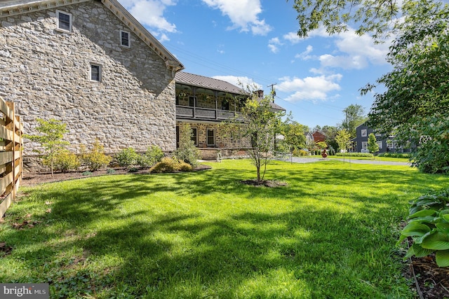 view of grassy yard featuring a balcony