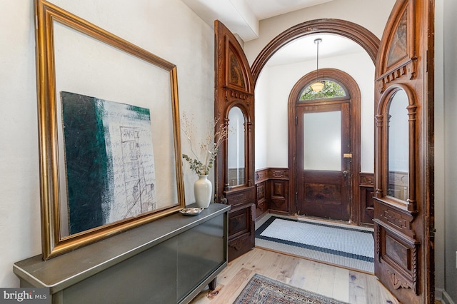 foyer with light wood finished floors and wainscoting