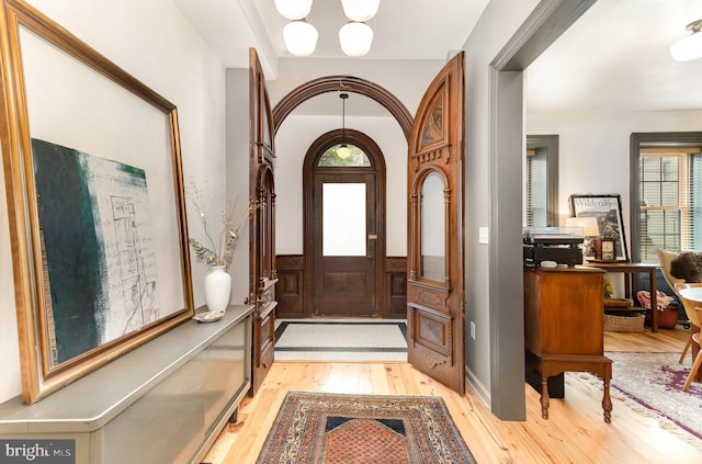 foyer entrance with light wood-style flooring, plenty of natural light, and a chandelier