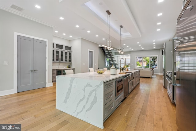 5706 Nevada Ave NW, Washington, DC 20015 - kitchen with a sink, crown molding, light wood-type flooring, light stone countertops, and a large island