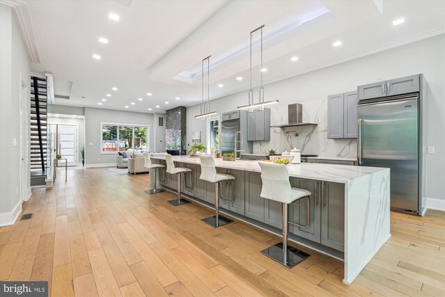 5706 Nevada Ave NW, Washington, DC 20015 - kitchen with stainless steel built in refrigerator, gray cabinetry, wall chimney exhaust hood, a large island, and light wood finished floors