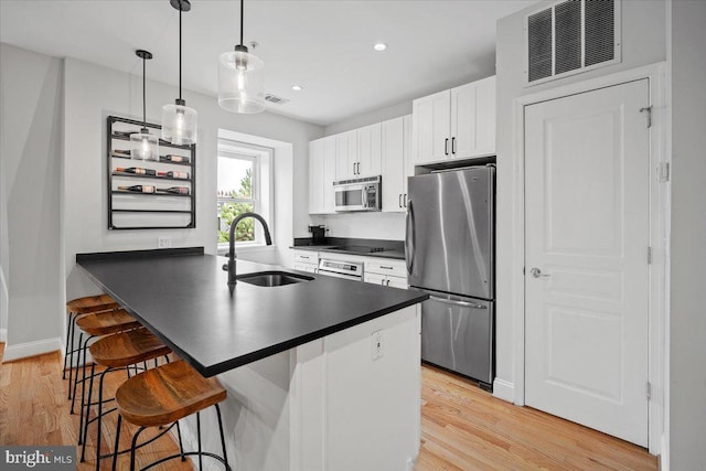 1407 15th St NW Unit 4, Washington, DC 20005 - kitchen featuring appliances with stainless steel finishes, a sink, dark countertops, a breakfast bar, and recessed lighting