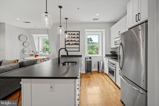 1407 15th St NW Unit 4, Washington, DC 20005 - kitchen featuring stainless steel appliances, a sink, dark countertops, white cabinets, and light wood-style floors