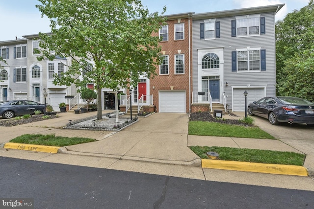 multi unit property with driveway, an attached garage, and brick siding