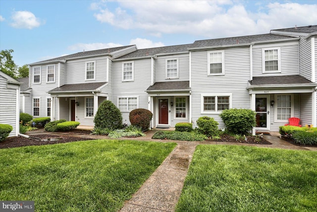 view of property featuring a front lawn and roof with shingles