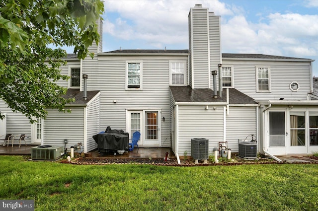 rear view of property with a patio area, central AC, and a lawn
