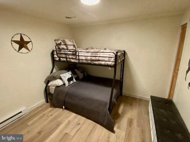 bedroom featuring a baseboard radiator, wood finished floors, and baseboards