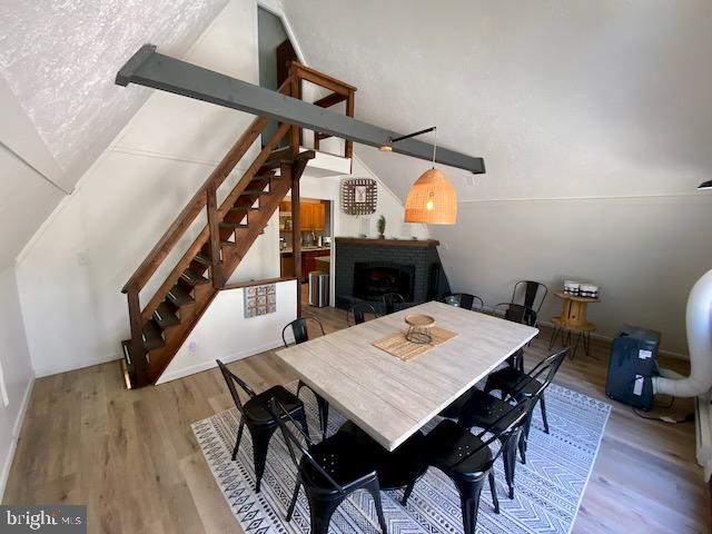 dining area with stairway, wood finished floors, and a brick fireplace