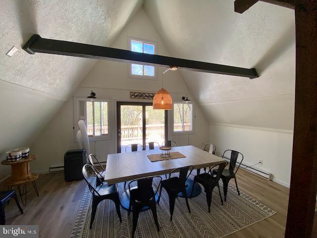 dining area featuring lofted ceiling, light wood-style floors, a baseboard radiator, and a textured ceiling