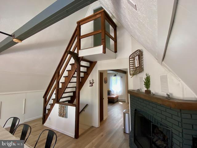 stairway featuring wood finished floors, a fireplace, wainscoting, and a decorative wall