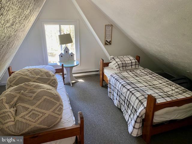 bedroom with a textured ceiling, carpet floors, vaulted ceiling, and a baseboard heating unit