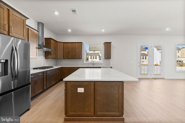 112 Heyford Dr, Stephenson, VA 22656 - kitchen with appliances with stainless steel finishes, wall chimney range hood, light wood-type flooring, a center island, and light stone counters