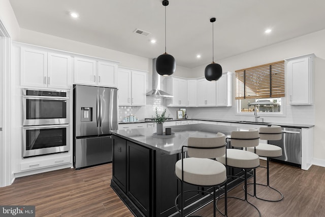 114 Heyford Dr, Stephenson, VA 22656 - kitchen with stainless steel appliances, wall chimney range hood, a center island, white cabinetry, and backsplash