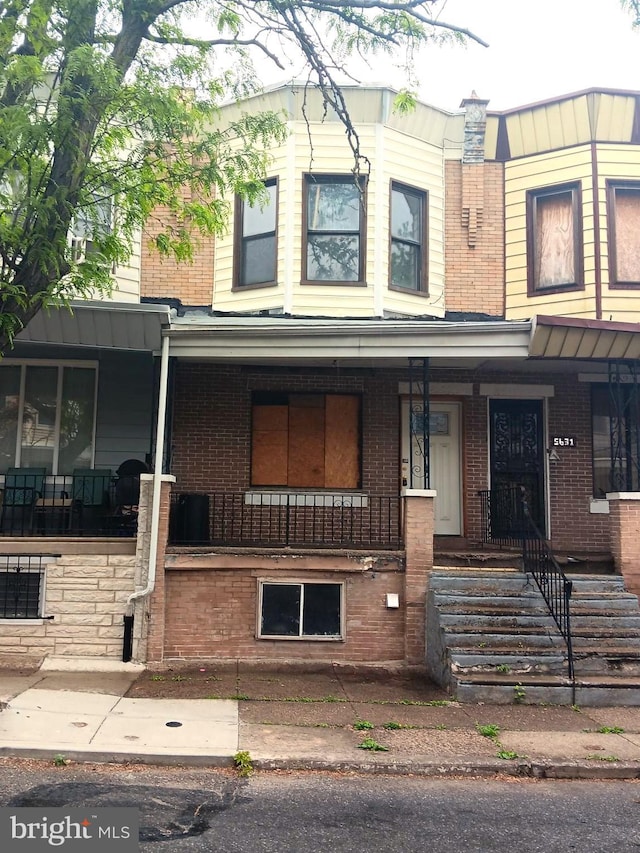 view of property featuring covered porch and brick siding