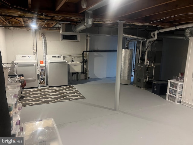 unfinished basement featuring water heater, washer and clothes dryer, heating unit, and a sink