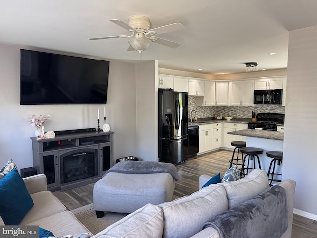 living area featuring a ceiling fan, wood finished floors, recessed lighting, and a glass covered fireplace