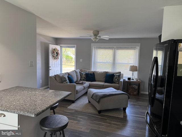 living room with a ceiling fan, dark wood-style floors, and baseboards