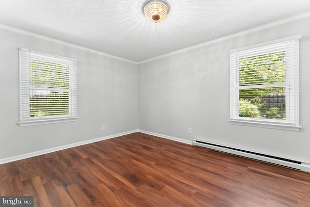 spare room featuring baseboard heating, wood finished floors, ornamental molding, and baseboards
