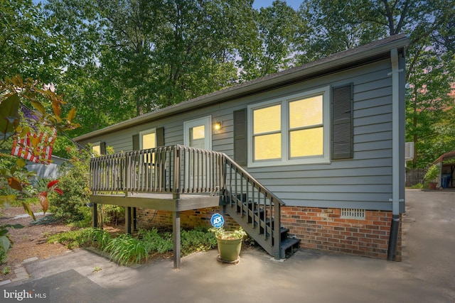 rear view of property featuring a wooden deck and crawl space