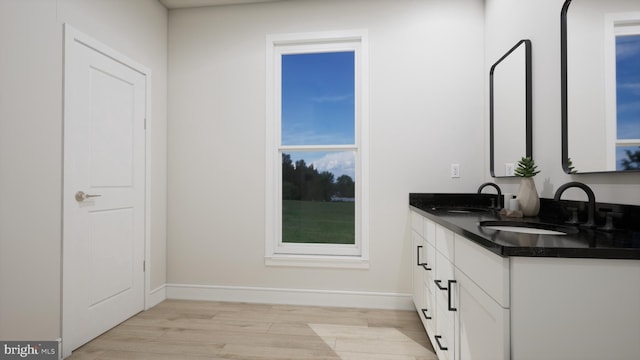 bathroom featuring wood finished floors, double vanity, and baseboards