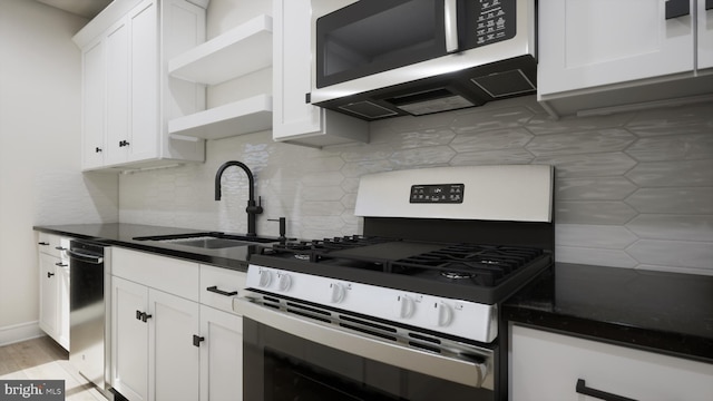kitchen with stainless steel appliances, a sink, open shelves, tasteful backsplash, and white cabinets