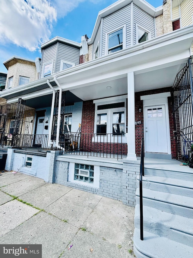 townhome / multi-family property featuring brick siding and covered porch