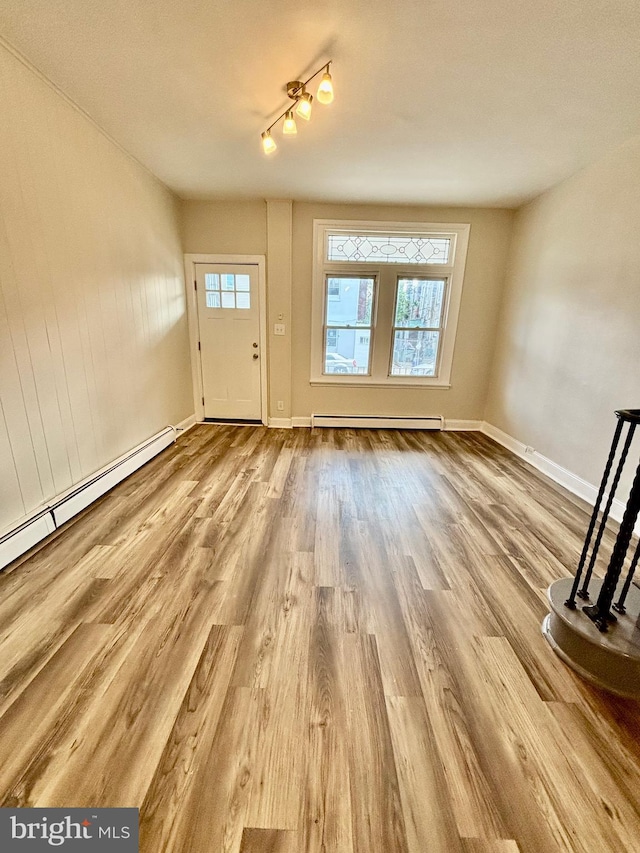 entryway featuring a baseboard heating unit, wood finished floors, baseboards, a baseboard radiator, and rail lighting