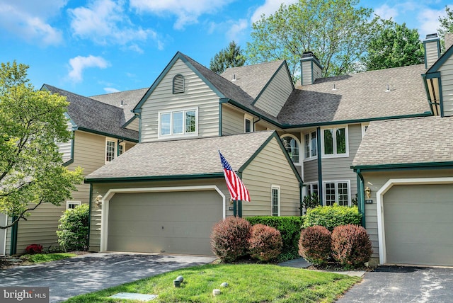 view of front of home featuring driveway, a garage, and a shingled roof