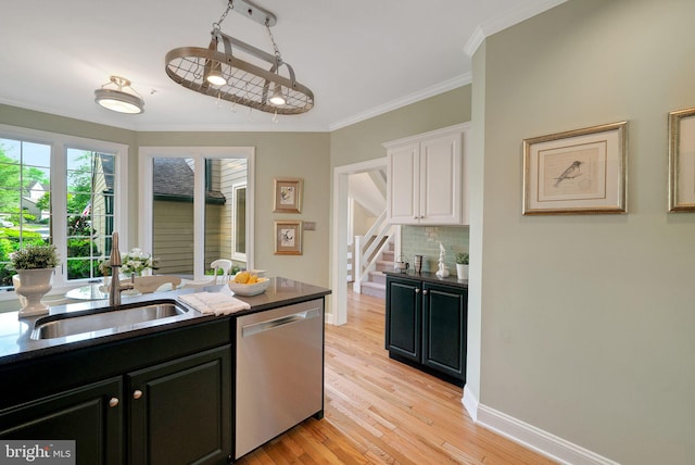 kitchen with dishwasher, dark cabinets, a sink, backsplash, and white cabinetry