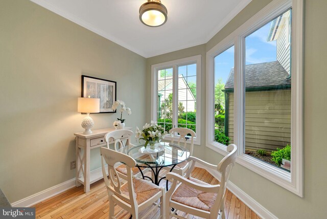 dining area with light wood-type flooring, baseboards, and ornamental molding