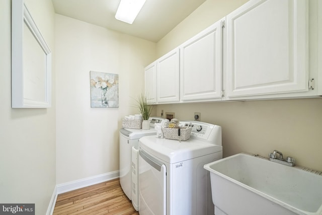 laundry room featuring washer and dryer, baseboards, cabinet space, and light wood-type flooring