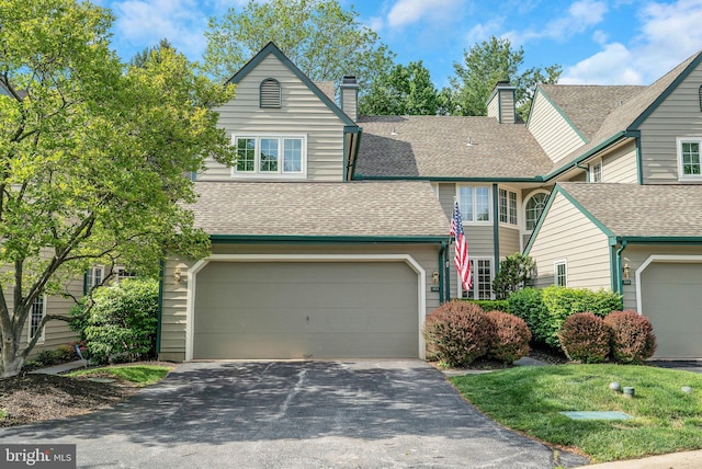 view of front of house featuring driveway, roof with shingles, an attached garage, and a chimney