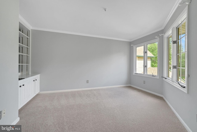 empty room with light colored carpet, crown molding, and baseboards