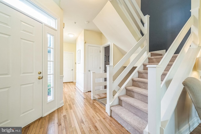 entrance foyer featuring light wood-style flooring, plenty of natural light, stairway, and baseboards