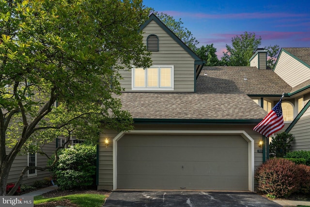 view of front of house featuring a shingled roof, asphalt driveway, and a garage