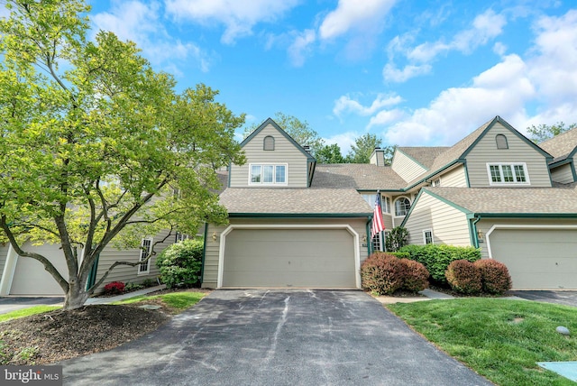 view of front of property featuring driveway, roof with shingles, and a garage