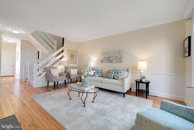 living room featuring hardwood / wood-style floors, ornamental molding, stairway, and baseboards
