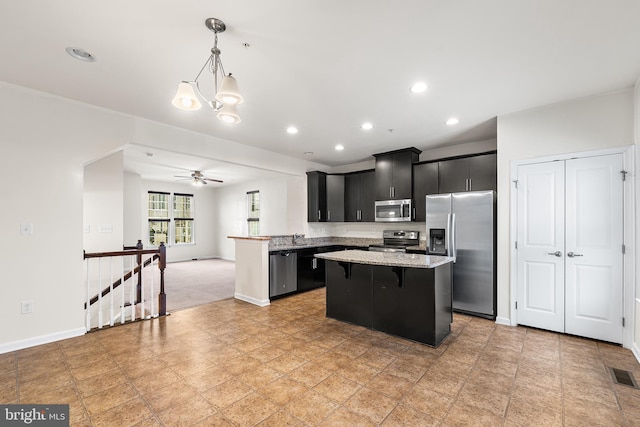 kitchen with stainless steel appliances, dark cabinetry, a kitchen island, a kitchen breakfast bar, and baseboards