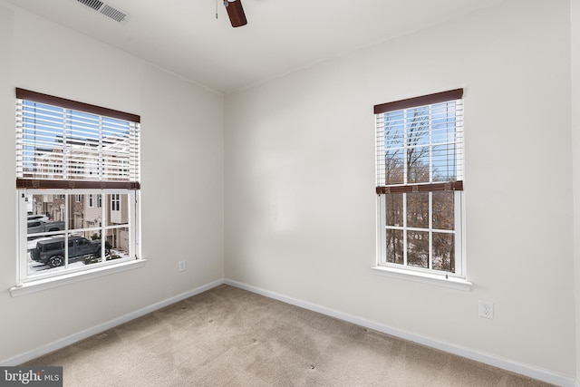 empty room with plenty of natural light, carpet floors, baseboards, and a ceiling fan