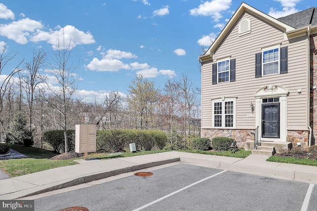 view of front of house featuring stone siding and uncovered parking