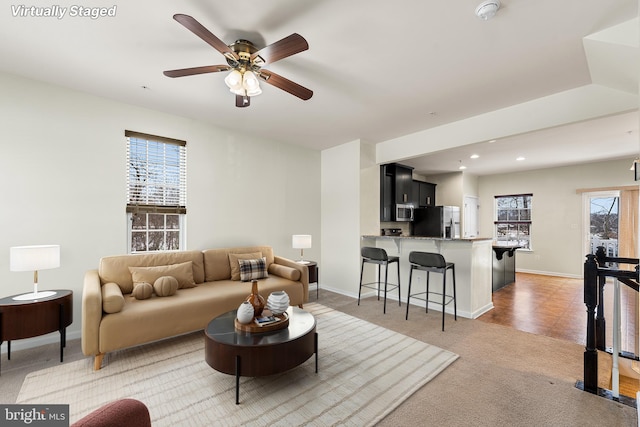 living area with recessed lighting, ceiling fan, baseboards, and light colored carpet