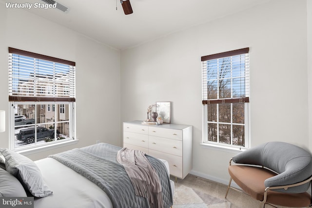 bedroom featuring light colored carpet, multiple windows, baseboards, and ceiling fan