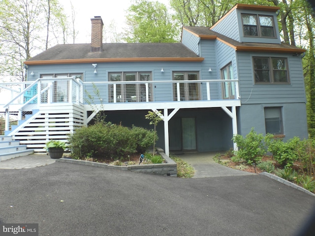 back of property featuring stairs, a chimney, and a deck