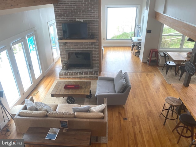 living area featuring wood finished floors, a brick fireplace, and healthy amount of natural light