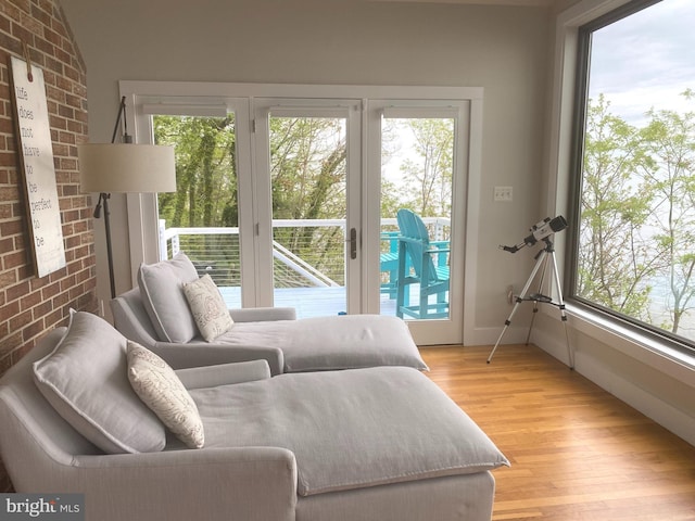 bedroom with access to exterior, multiple windows, and brick wall